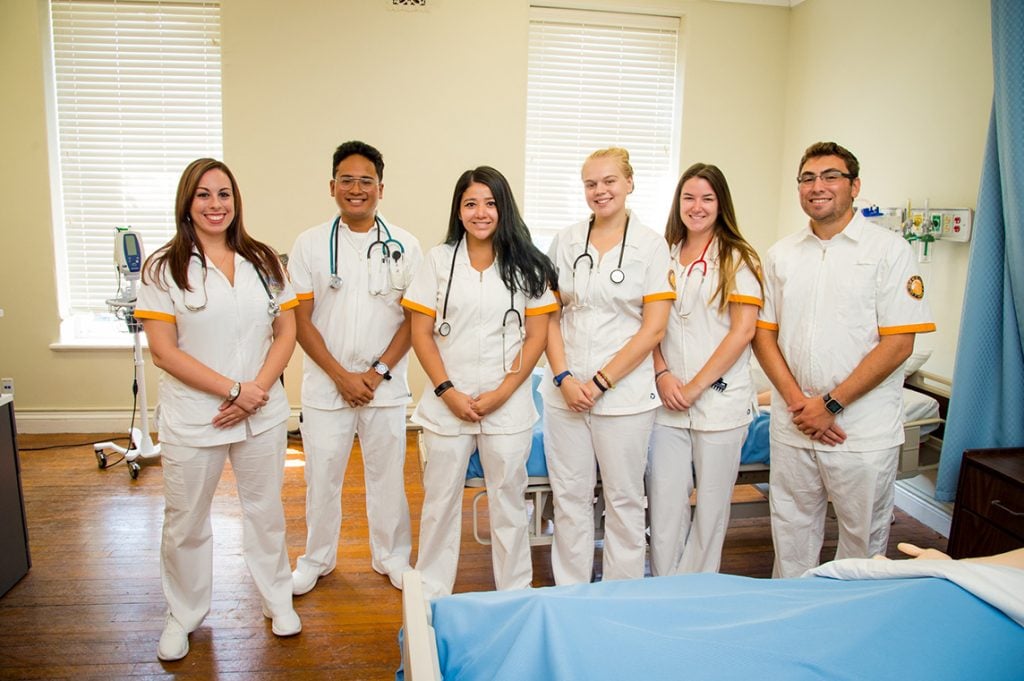 6 nurses standing in row in hospital setting