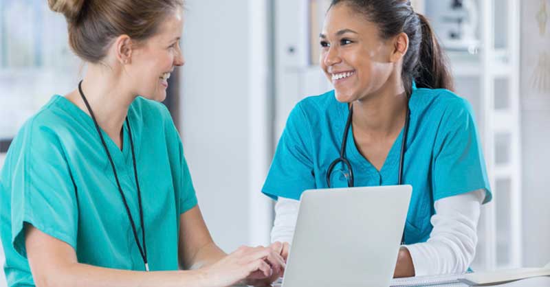 nurses talking together while standing at hospital desk