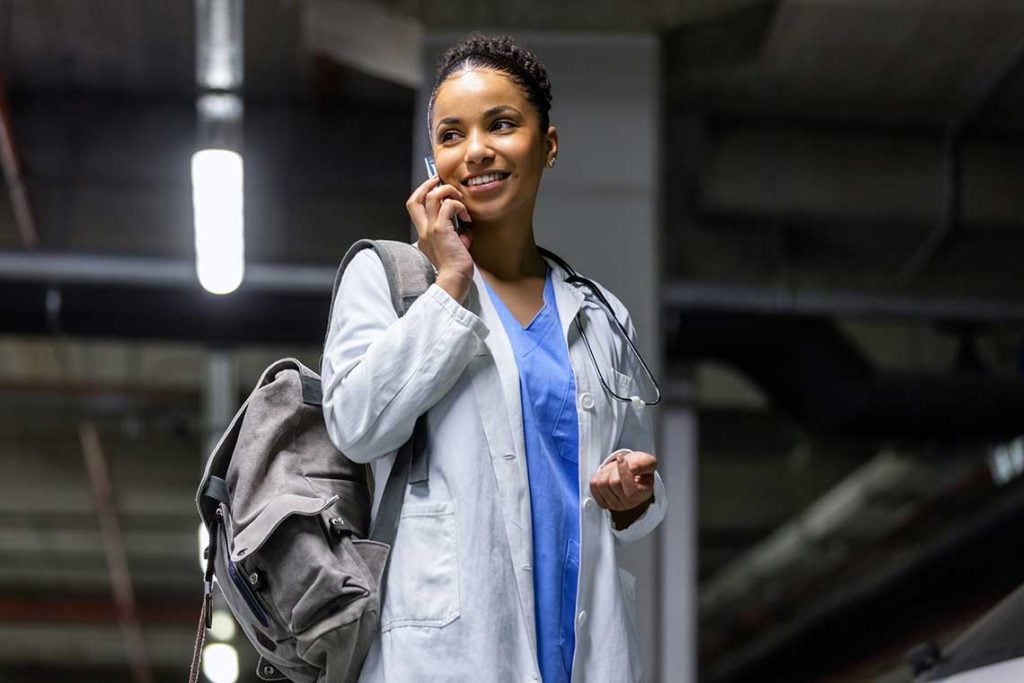 nurse standing in parking lot talking on phone