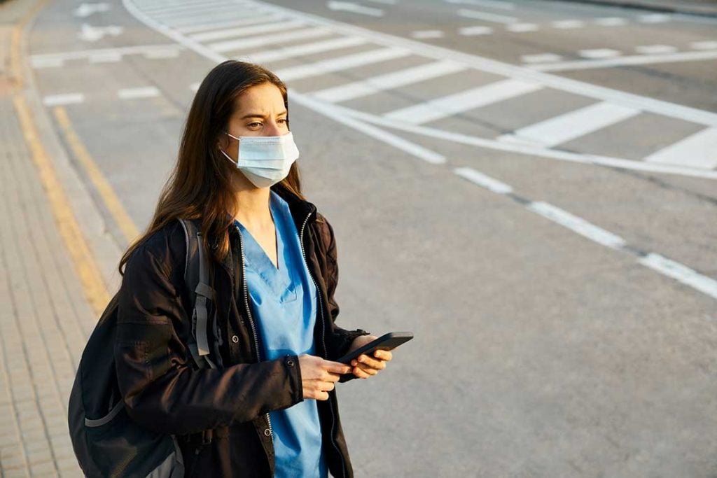 nurse wearing face mask standing on side of road