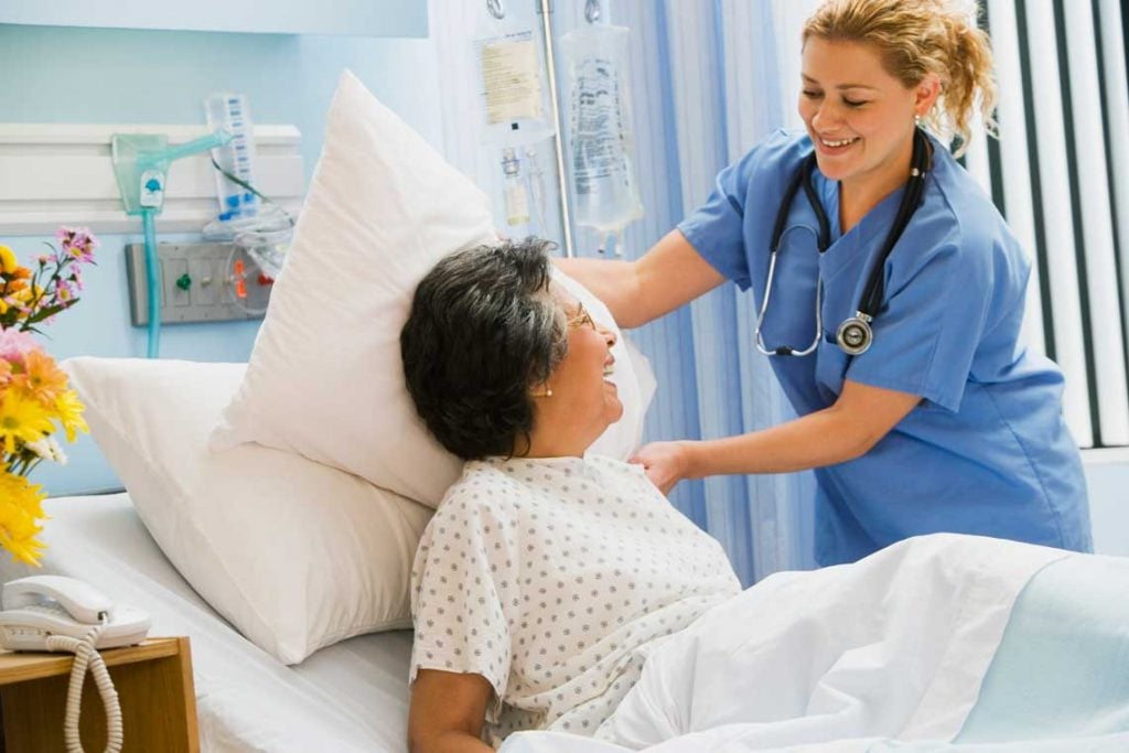 nurse adjusts patient's pillow