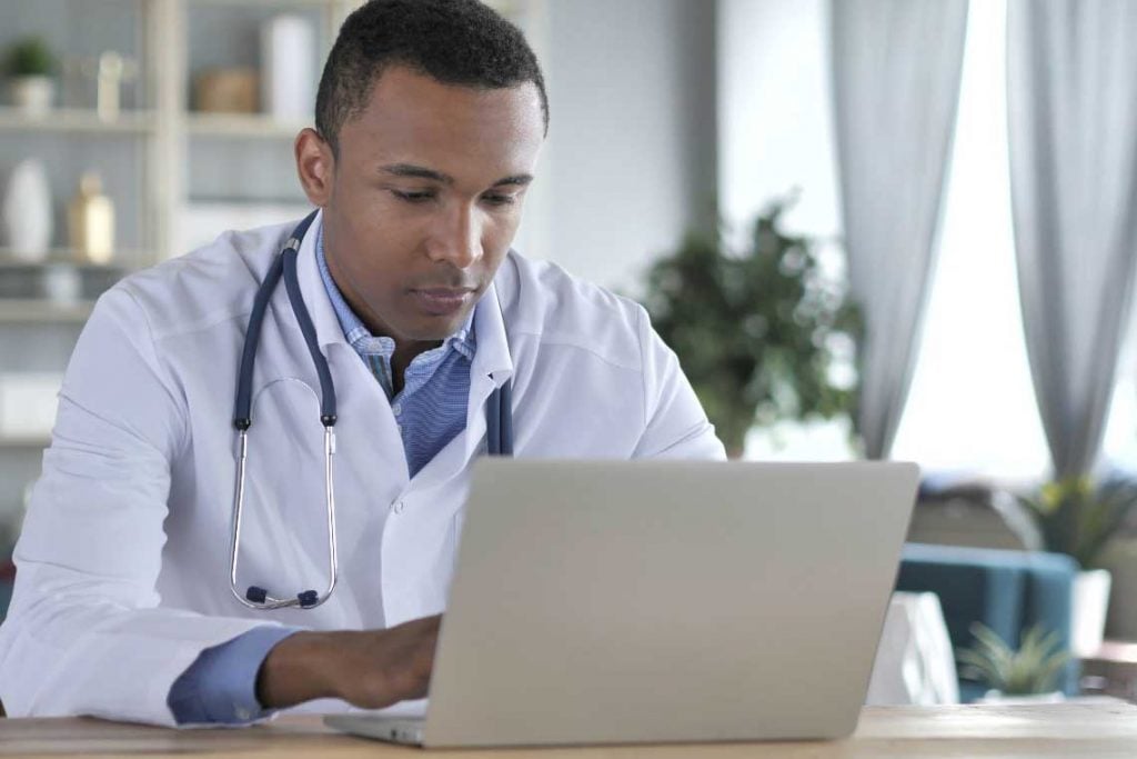 doctor typing on laptop