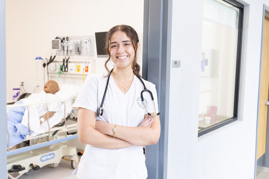 Nursing student leaning in doorway of sim lab