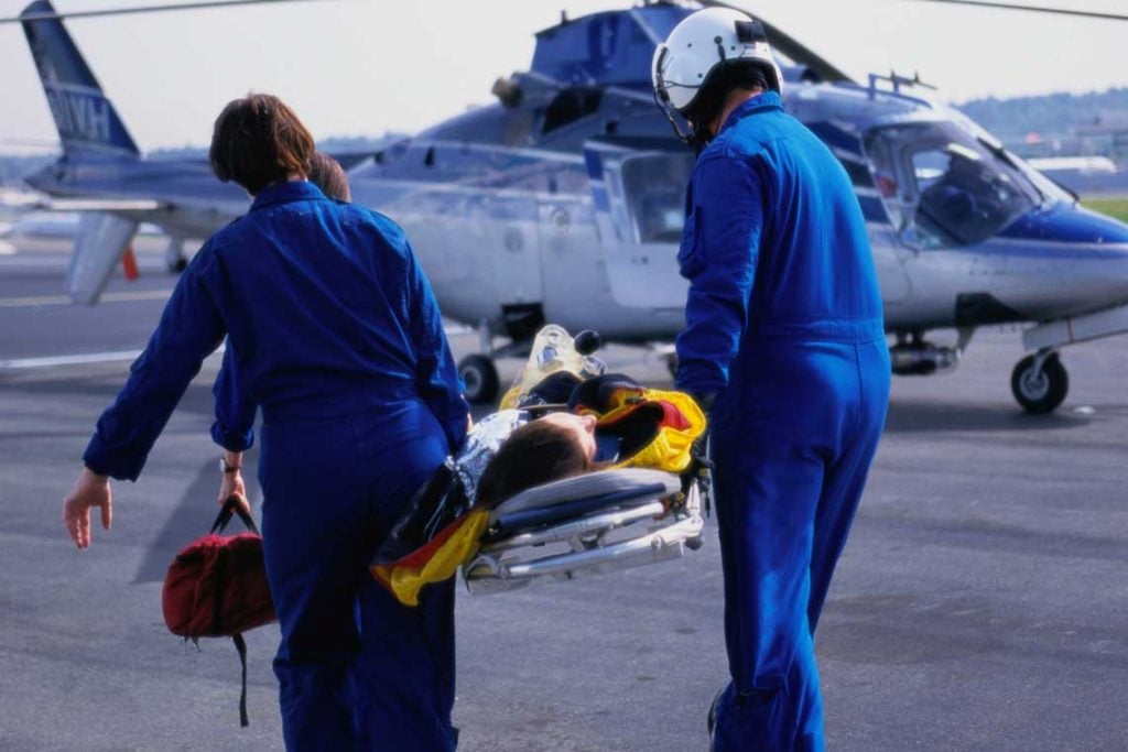 emergency personnel carrying patient to helicopter