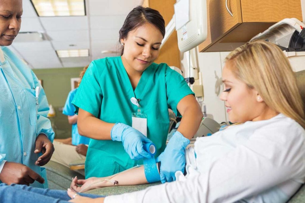 nurse wrapping gauze on patient's arm