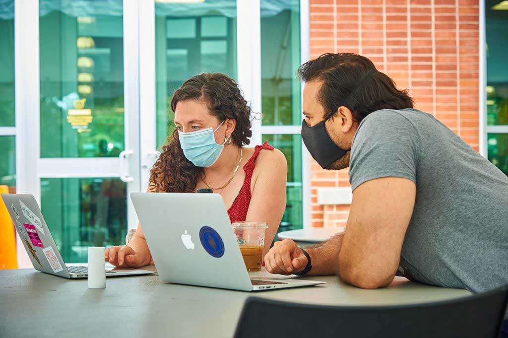 two people looking at laptops at desk