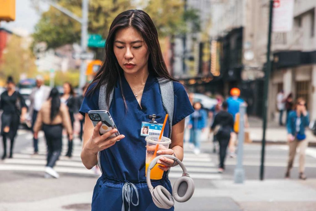 nurse walking outside with phone and drink