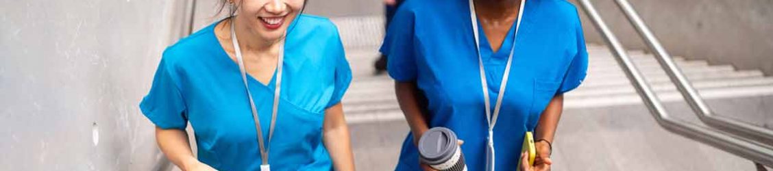 Two nurses walking up a flight of stairs smiling