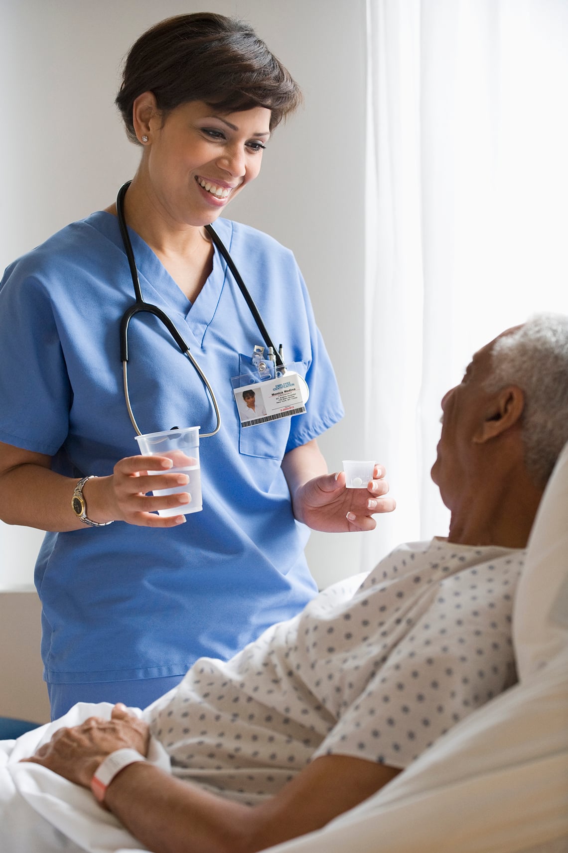 Nurse handing meds to a patient in hospital bed