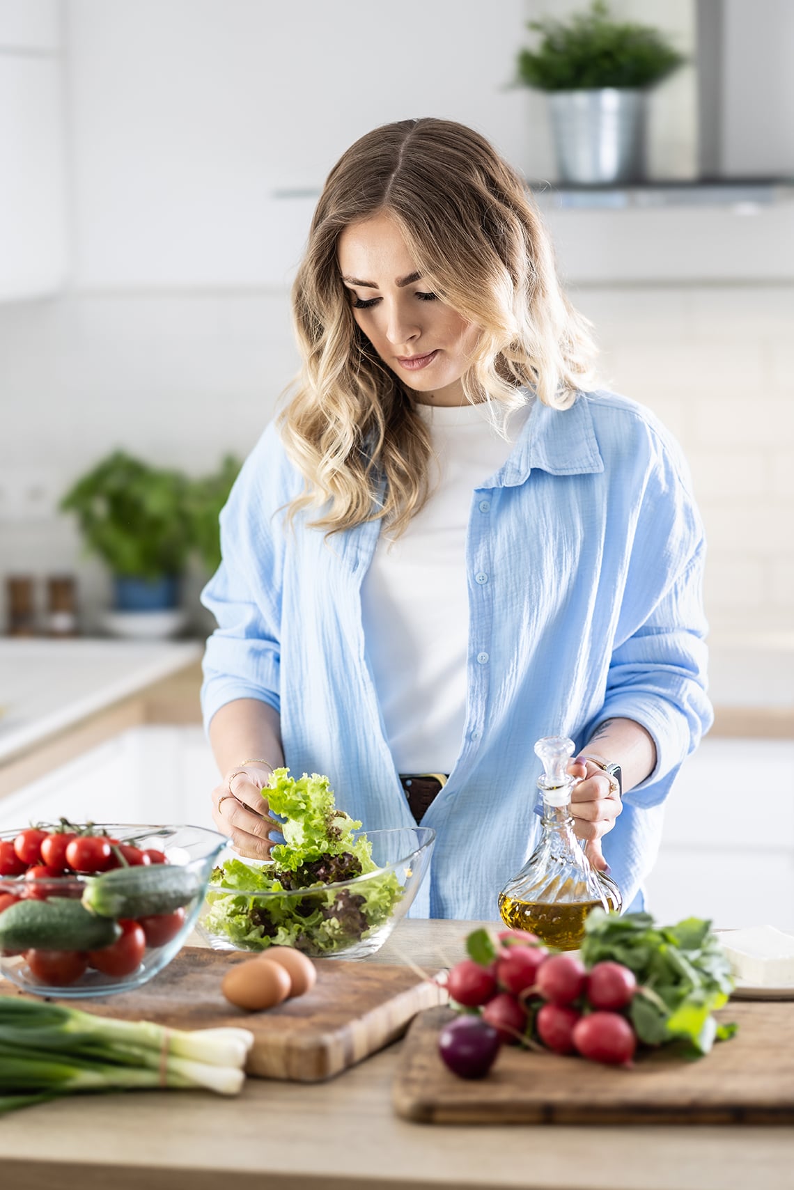 Woman in kitchen with vegetables and salad oil